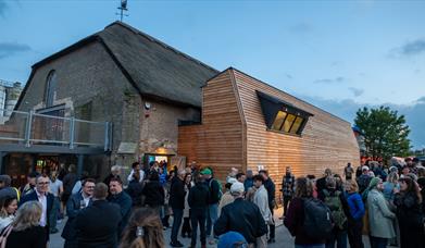 Thatched building with balcony and people gathering outside