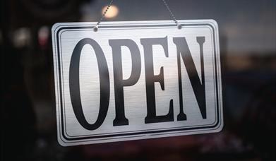 Silver open sign in glass door