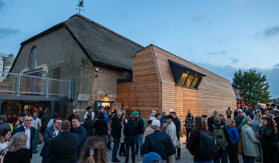 Thatched building with balcony and people gathering outside
