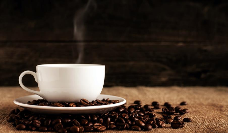 Cup of coffee surrounded by coffee beans