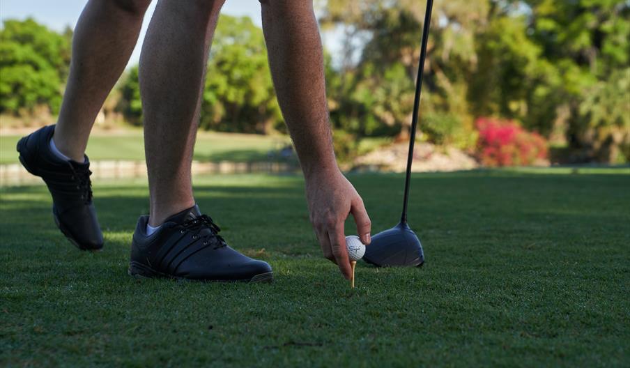 Man placing golf ball on tee