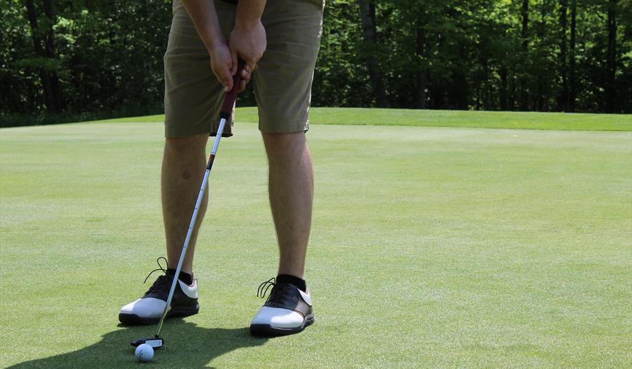 Man about to putt golf ball