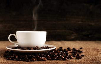 Cup of coffee surrounded by coffee beans