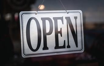 Silver open sign in glass door