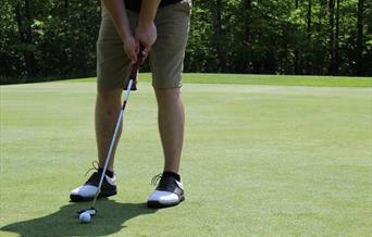 Man about to putt golf ball