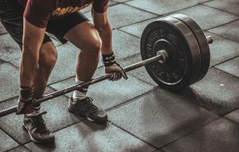 Man in shorts and trainers with gloves on about to lift weight