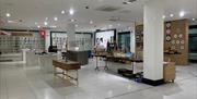 interior of gallery. white space with columns. shop area depicted with items displayed on tables and walls