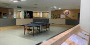 interior of gallery space showing central area with table tennis table surrounded by artworks displayed on the walls.