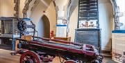 A display of objects at Tolhouse Gaol. At the front is a wooden cart with red wooden wheels. It was used to transport prisoners