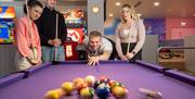 Group of friends playing american pool at Richardson's Family Entertainment Centre