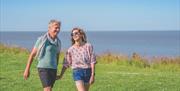 A couple walks along the clifftop at Potters Resorts Hopton-on-Sea
