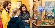 Three people looking at an automaton model of a fairground on Wellington Pier