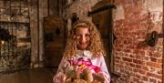 A child holds a wooden plate with models of food that prisoners ate at the Gaol. The food includes potato, bread and gruel. There is also a large wood
