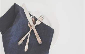 Knife, folk and spoon on blue napkin and white plate