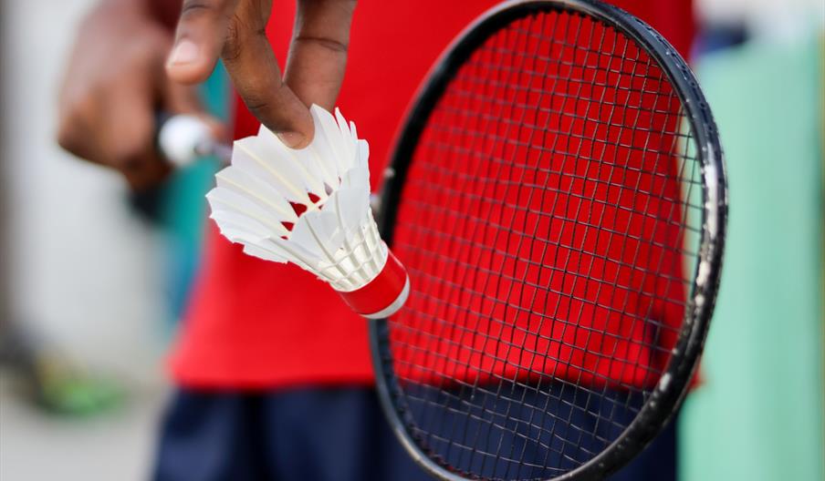 Person holding black badminton racket about to hit shuttlecock